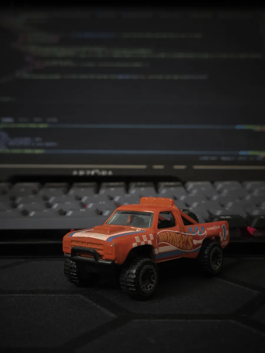 Toy pickup truck on a keyboard in front of a code editor