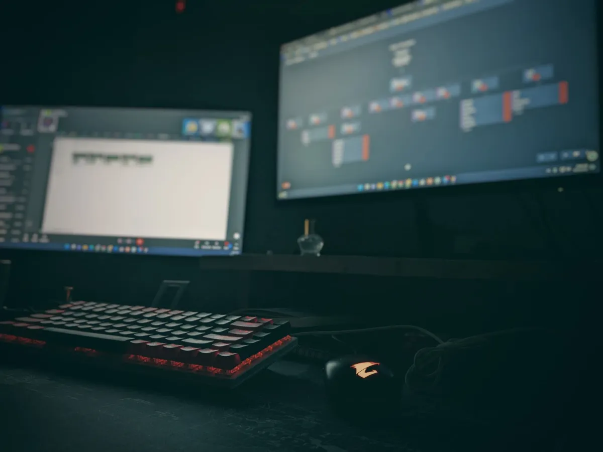 Desk setup at night with dual monitors and a backlit keyboard