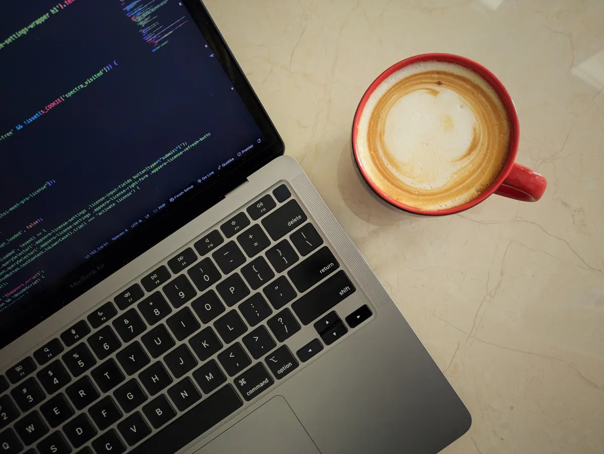 Laptop with code beside a cup of latte